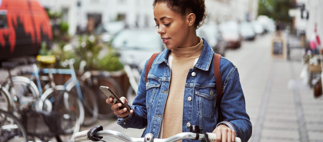 young female riding bike and looking at phone