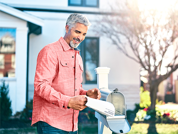 A man picks up the mail from his mailbox.