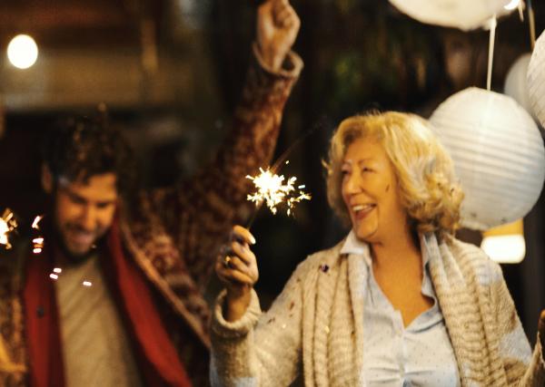 An older woman and her son celebrate New Year’s with sparklers.