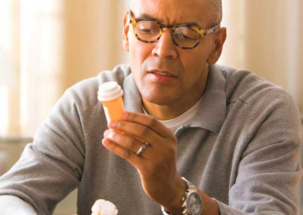 An older man reads the label on a prescription.