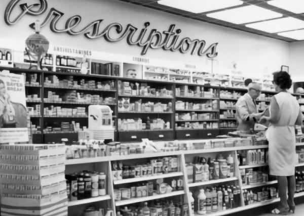 A pharmacist rings up a customer at the register of a neighborhood pharmacy in the 1950s.
