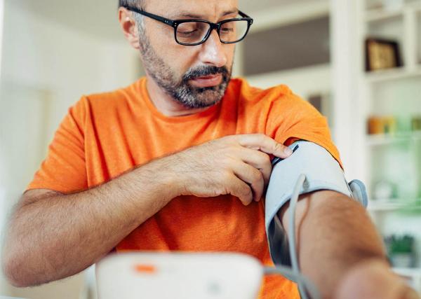 A man checks his blood pressure using a blood pressure cuff.
