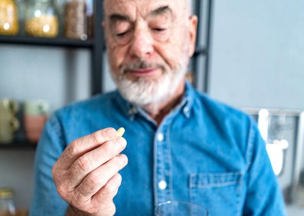 A man examines a pill in his hand, wondering if it can be split safely.