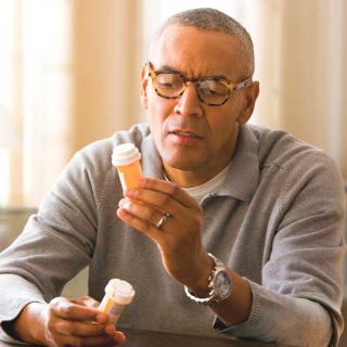 An older man reads the label on a prescription.