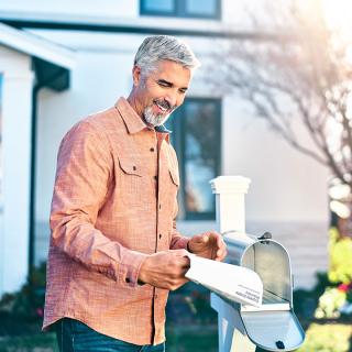 A man holds his recently delivered prescription outside his home mailbox.