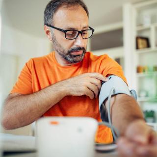 A man checks his blood pressure using a blood pressure cuff.