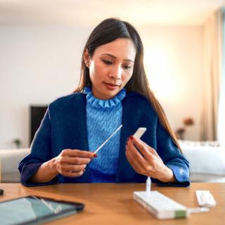 A woman looks at the results of her at-home COVID-19 test.