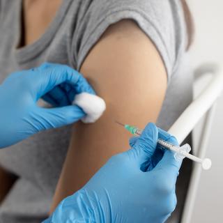 The arm of a woman receiving a vaccination is shown.